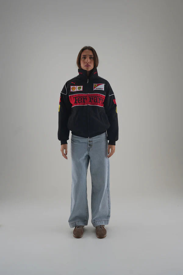 Person wearing a black ferrari jacket with red and white text on a gray background