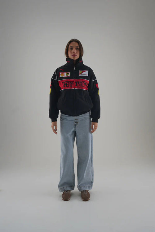 Person wearing a black ferrari jacket with red and white text on a gray background