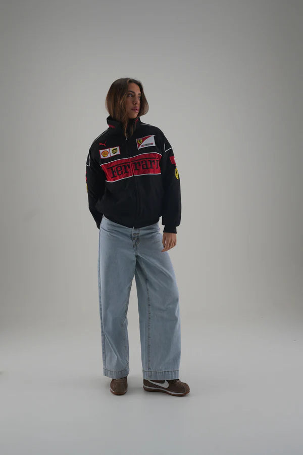 Person wearing a black ferrari jacket with colorful text and graphics on a plain background