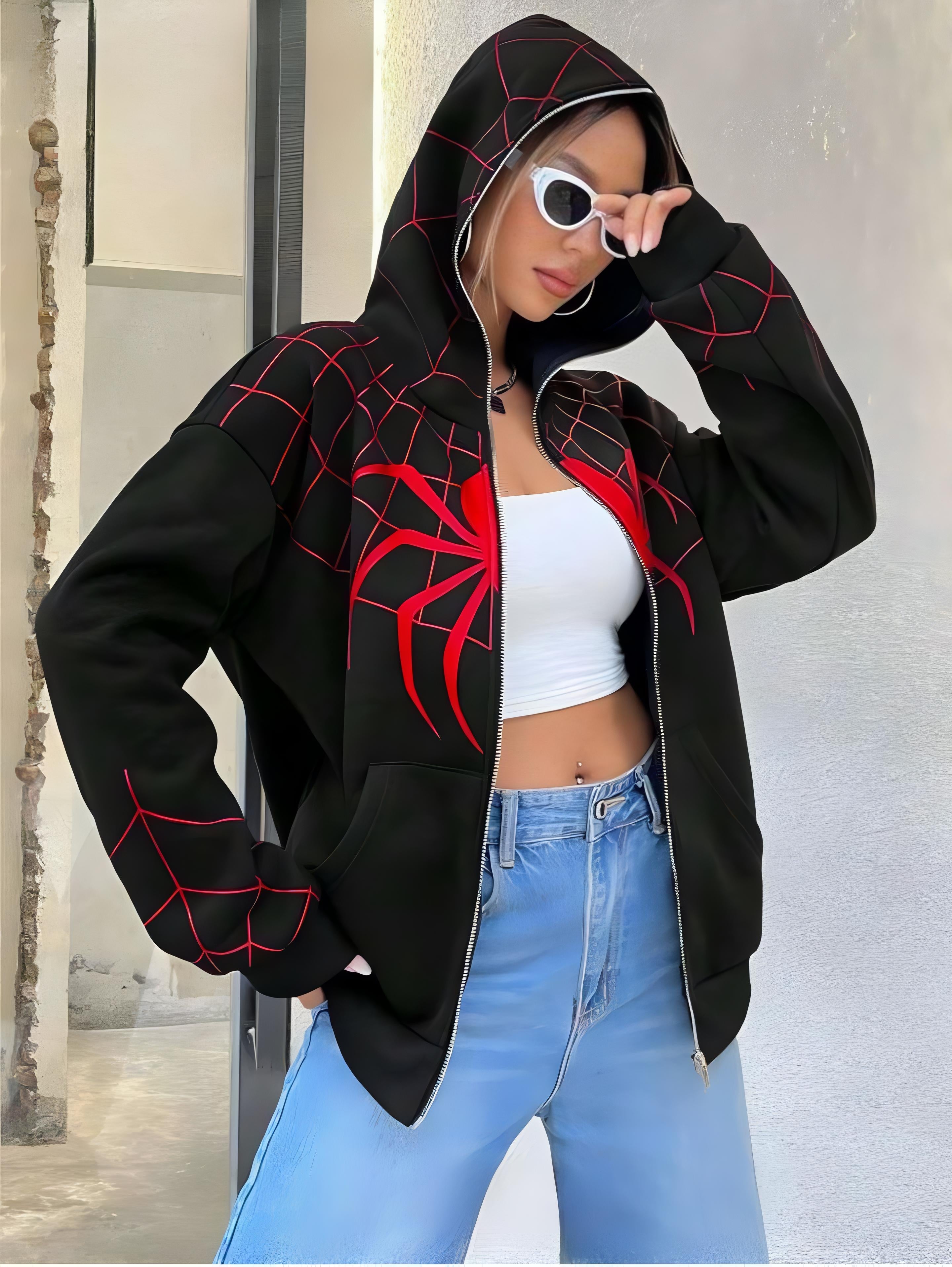 Person wearing a black hoodie with red spider designs, white crop top, and blue jeans.