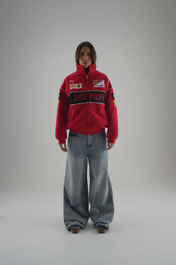 Person wearing a red ferrari jacket with logos on a plain background