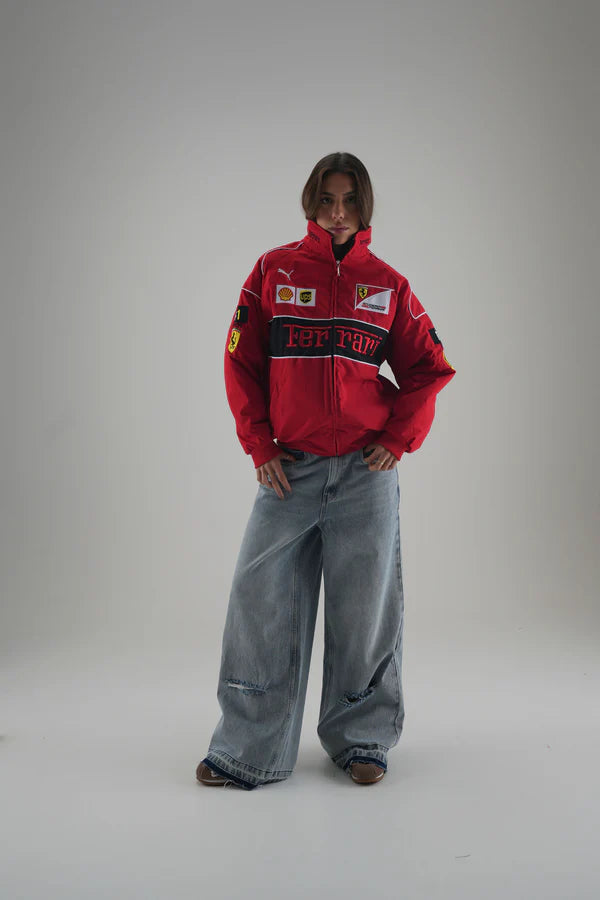 Person wearing a red ferrari jacket with logos on a gray background