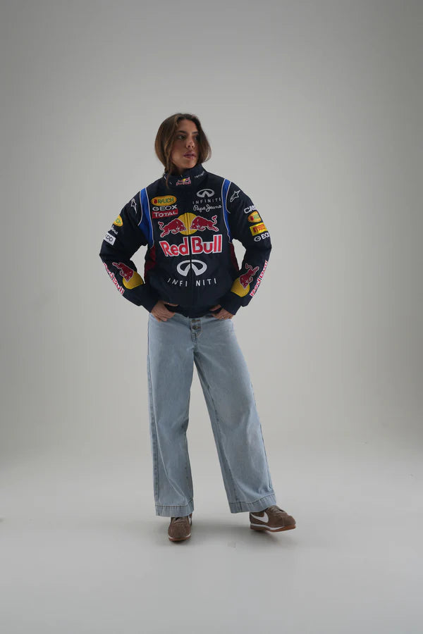 Person wearing a Red Bull sweater with various logos on a plain background