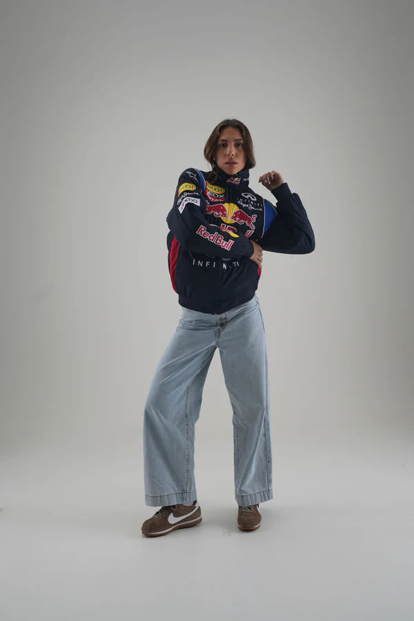 Person wearing a Red Bull sweatshirt and jeans on a plain background