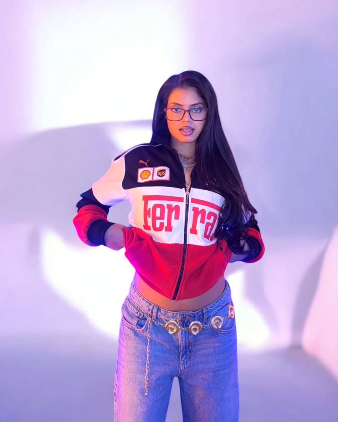 Person wearing a colorful jacket with branding and jeans against a white background