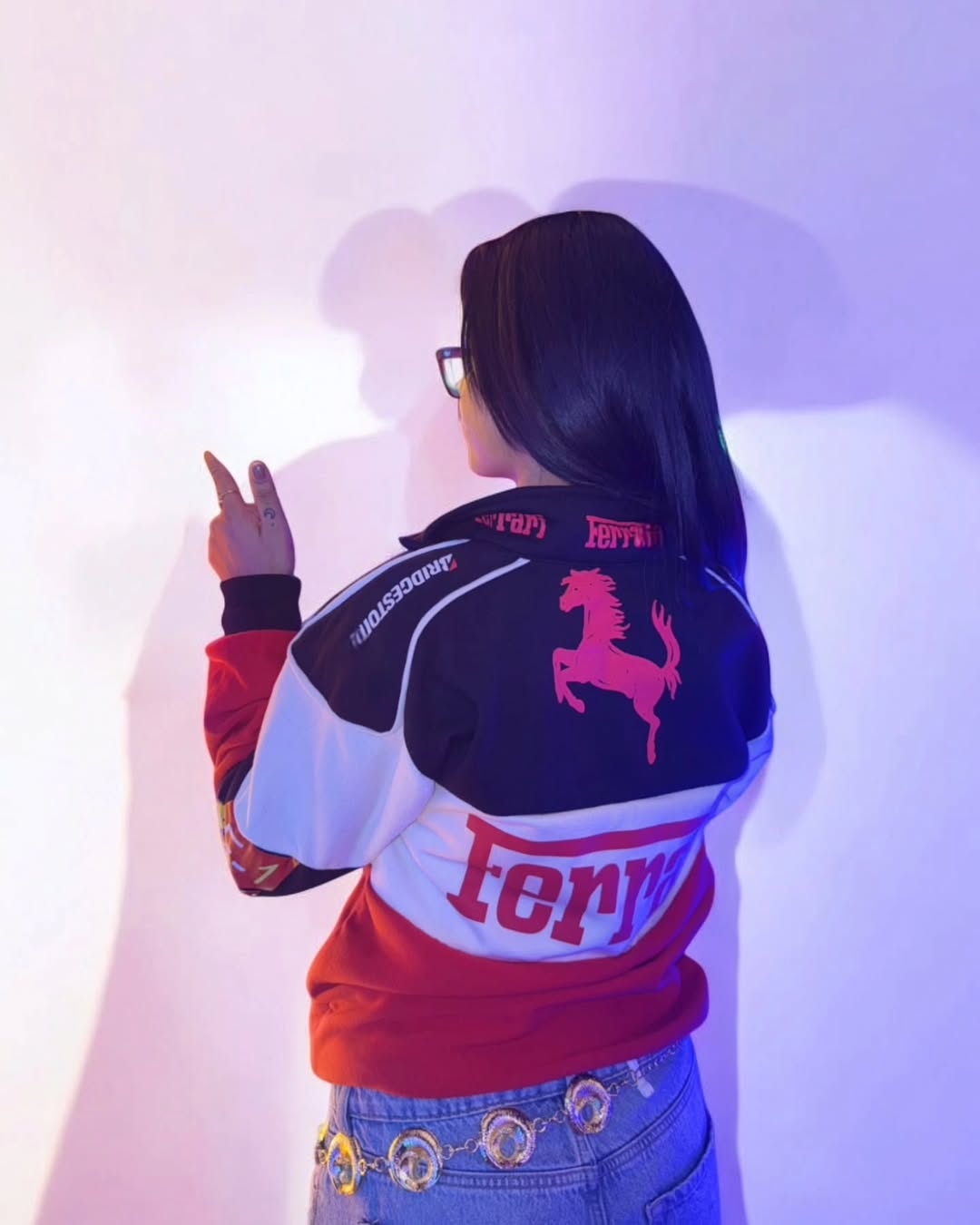 Person wearing a colorful jacket with a horse logo and text, standing against a light background.