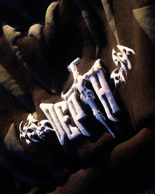 Close-up of a brown garment with white embroidered designs on a dark background