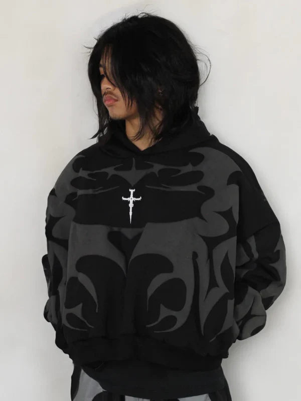 Person wearing a black hoodie with a white cross design on a white background