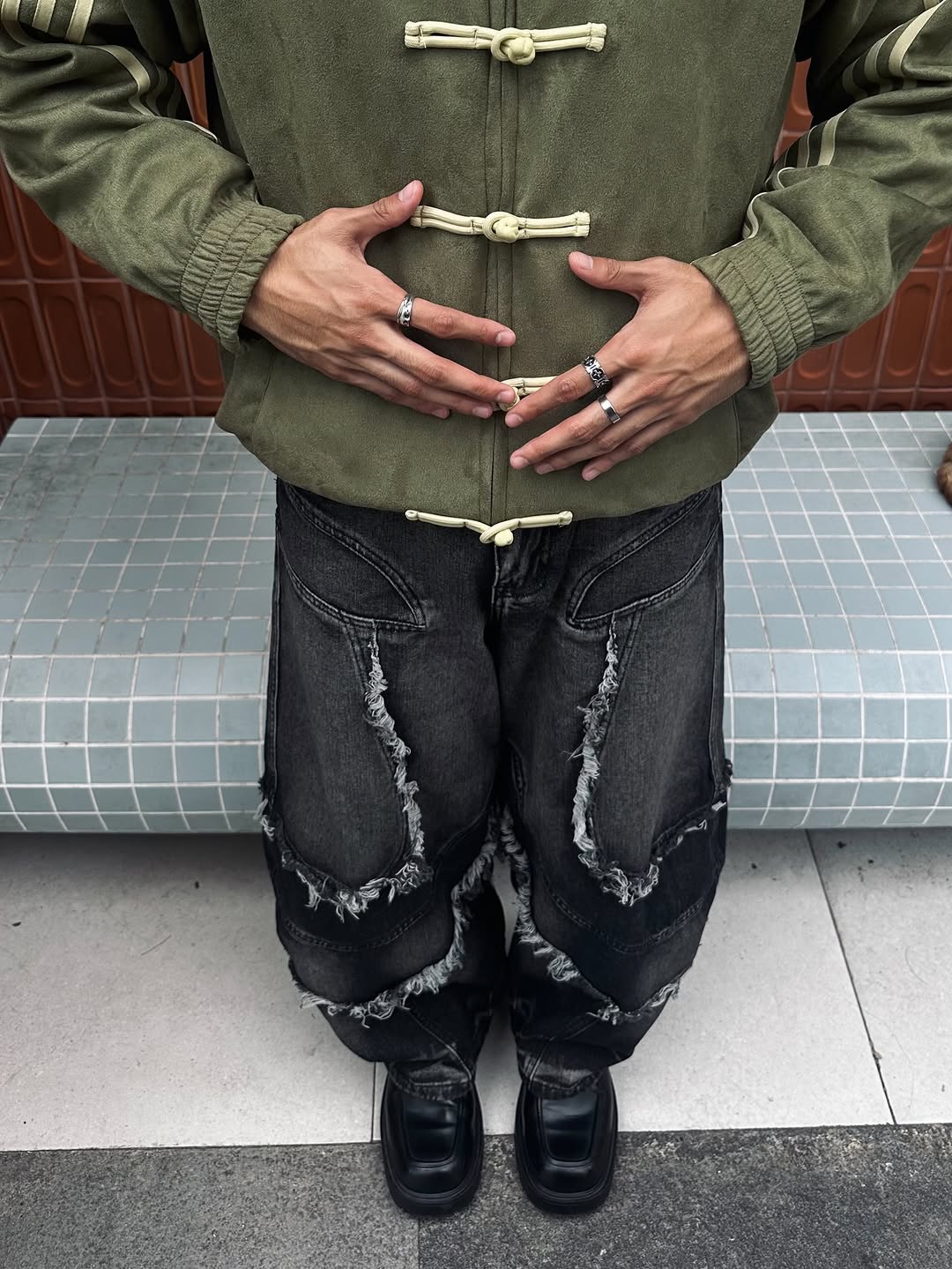 Full body style shot showing the male model layering the Olive Green CNY Suede Jacket exactly as intended. Paired with heavy streetwear cargo pants to push the aggressive, wide Gen-Z streetwear silhouette.