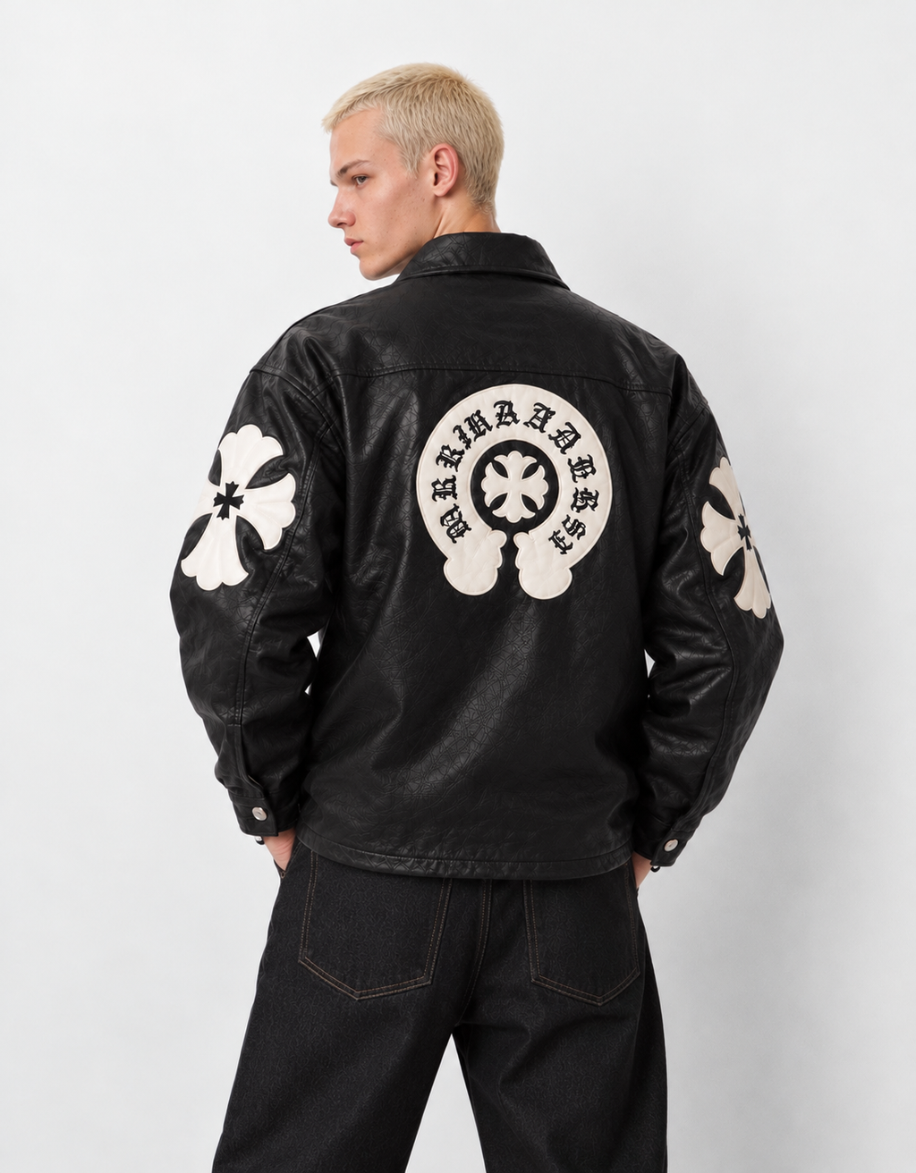 Back angle of a male model in the black Gothic leather jacket, emphasizing the tonal stitched leather cross patches across the back and sleeves