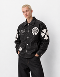 Front view of a boy styling the black leather cross patch jacket, showing the functional side welt pockets and silver snap buttons
