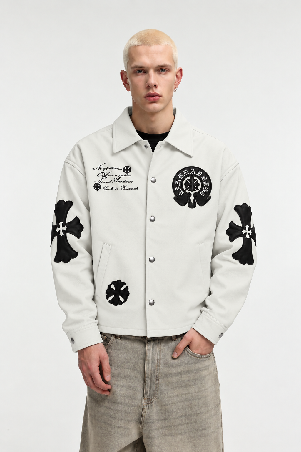 Front angle of a male model in the cream cross patch jacket, highlighting the silver-tone snap button closures and chest script embroidery