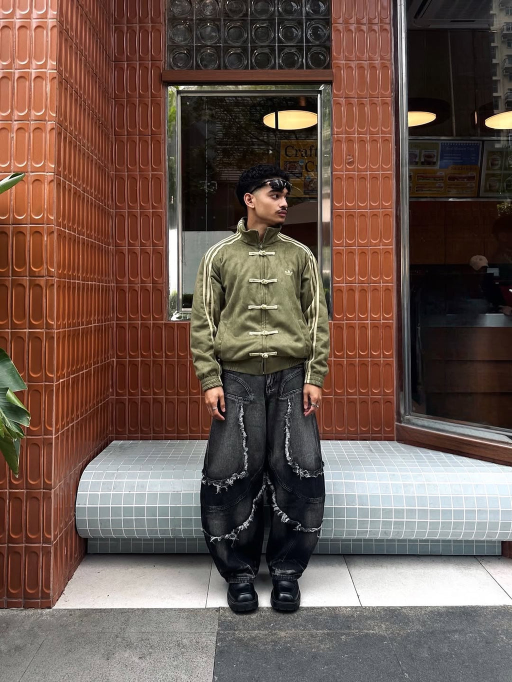 Candid walking shot of the male model wearing the Streetbred Olive Green CNY jacket. Highlights the natural drape, thermal heaviness, and wind-breaking capabilities of the luxurious 420 GSM suede material.