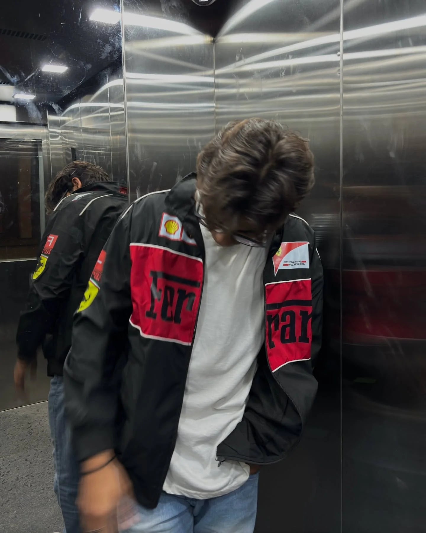 Front view of a male model wearing the oversized Streetbred Black Ferrari F1 Jacket over a hoodie.