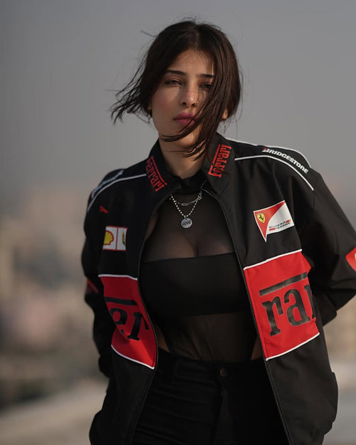 Front view of a female model wearing the unisex Streetbred Black Ferrari F1 Jacket with baggy streetwear pants.