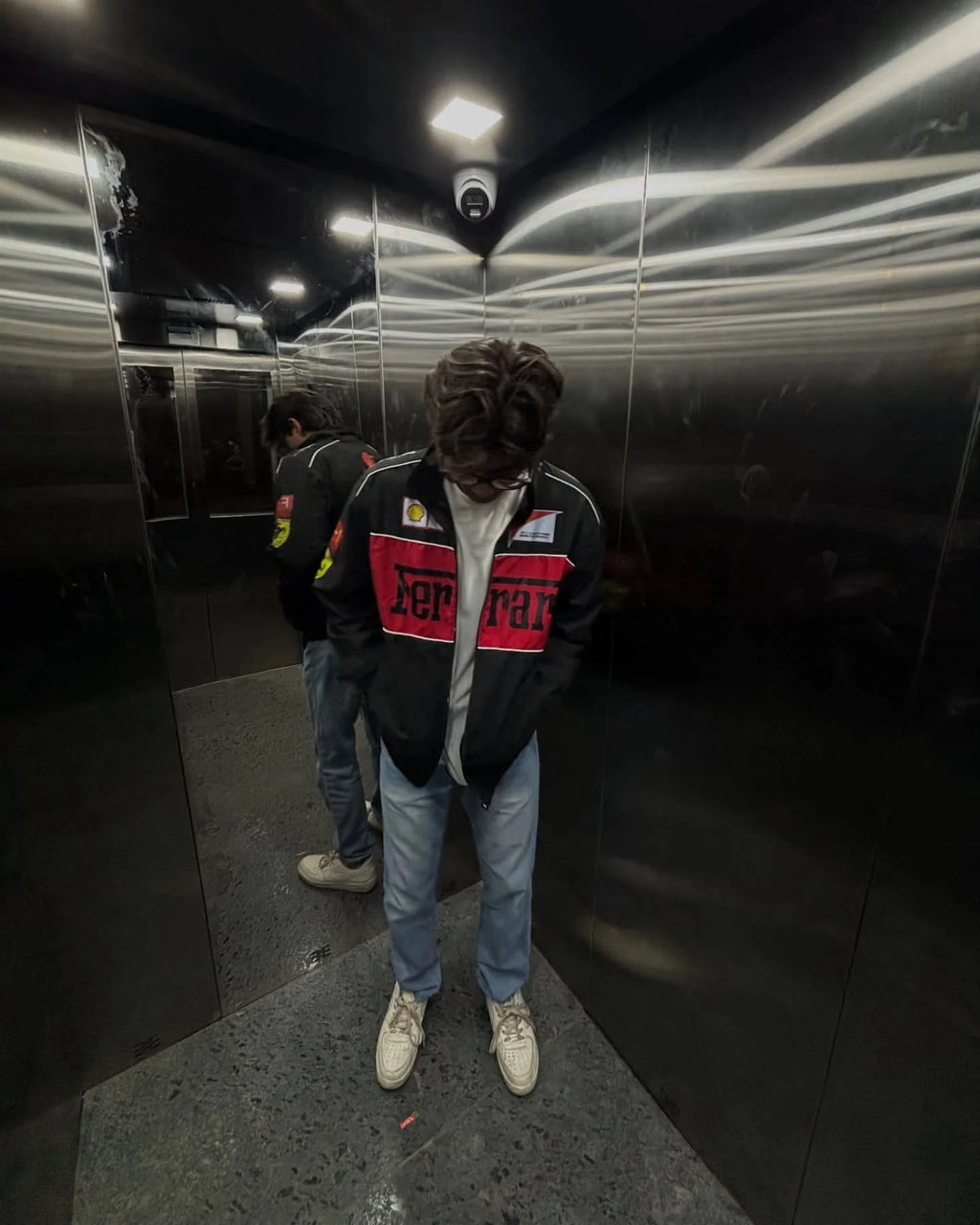 Male model styling the Streetbred Black Ferrari F1 Jacket with wide-leg track pants for an urban racing look.