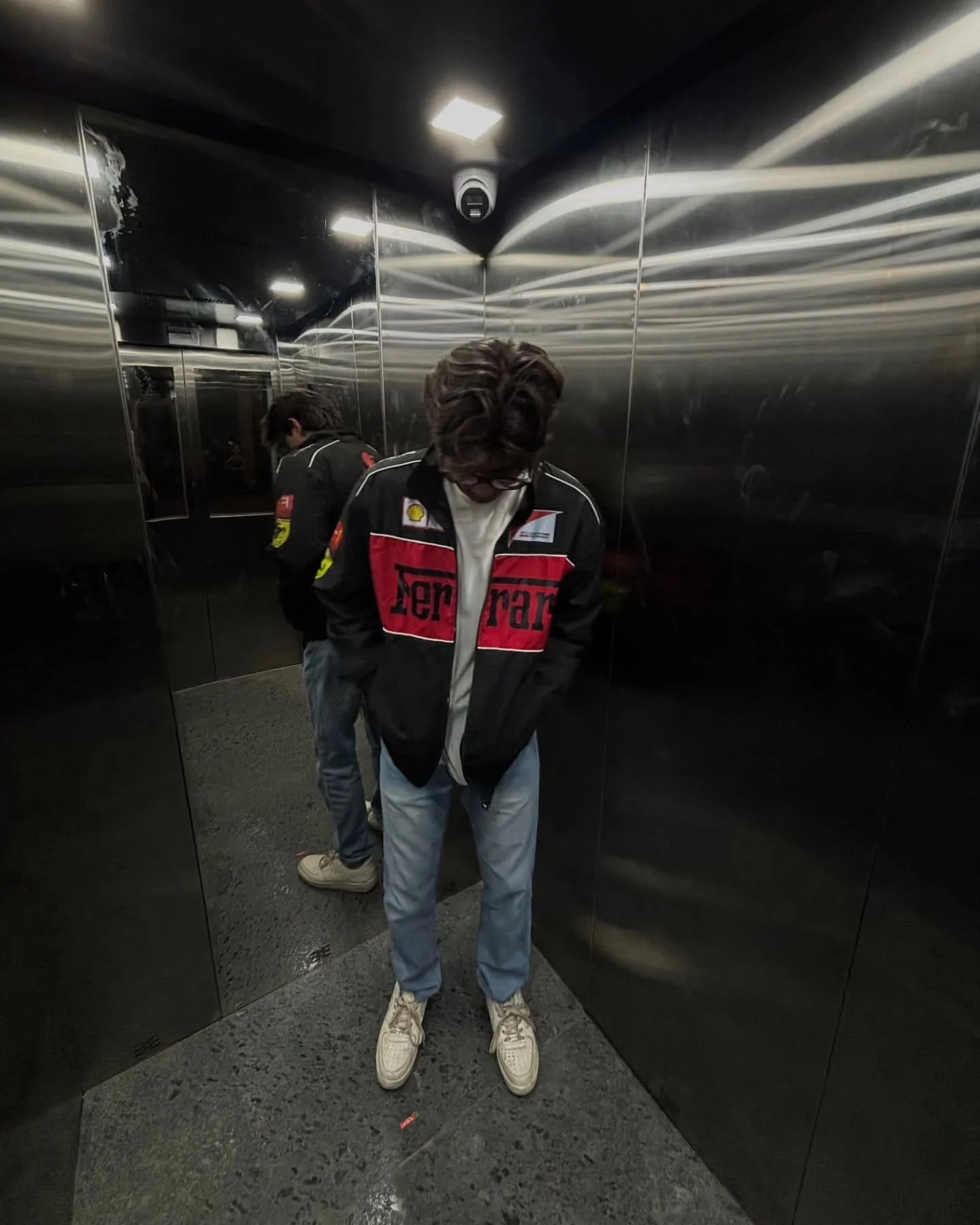 Male model styling the Streetbred Black Ferrari F1 Jacket with wide-leg track pants for an urban racing look.