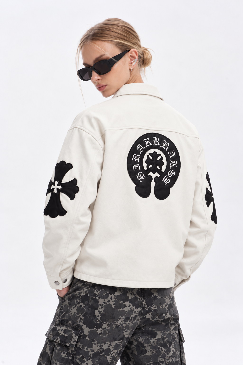Female model showing the back of the off-white Gothic cross jacket with stitched black leather cross appliqués and horseshoe crest